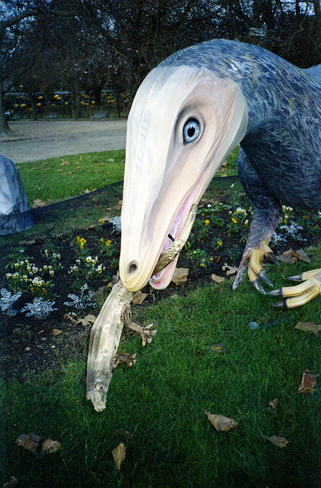 a sculpture of a middle-sized dinosaur eating a small lizard